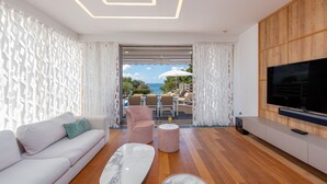 Una sala de estar moderna con un sofá, dos sillones, una mesa de centro y un televisor.