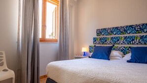 A bedroom with a bed, curtains, a nightstand, a lamp, and a chair. - Apple House (Giardini Naxos)