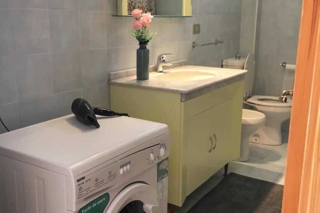 A compact bathroom with a washing machine, a sink, and a toilet.