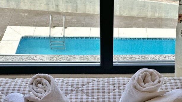 Vista desde una ventana: piscina con suelo a cuadros y escalera.