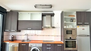 Una cocina compacta equipada con lavavajillas, lavadora, microondas, horno y refrigerador.