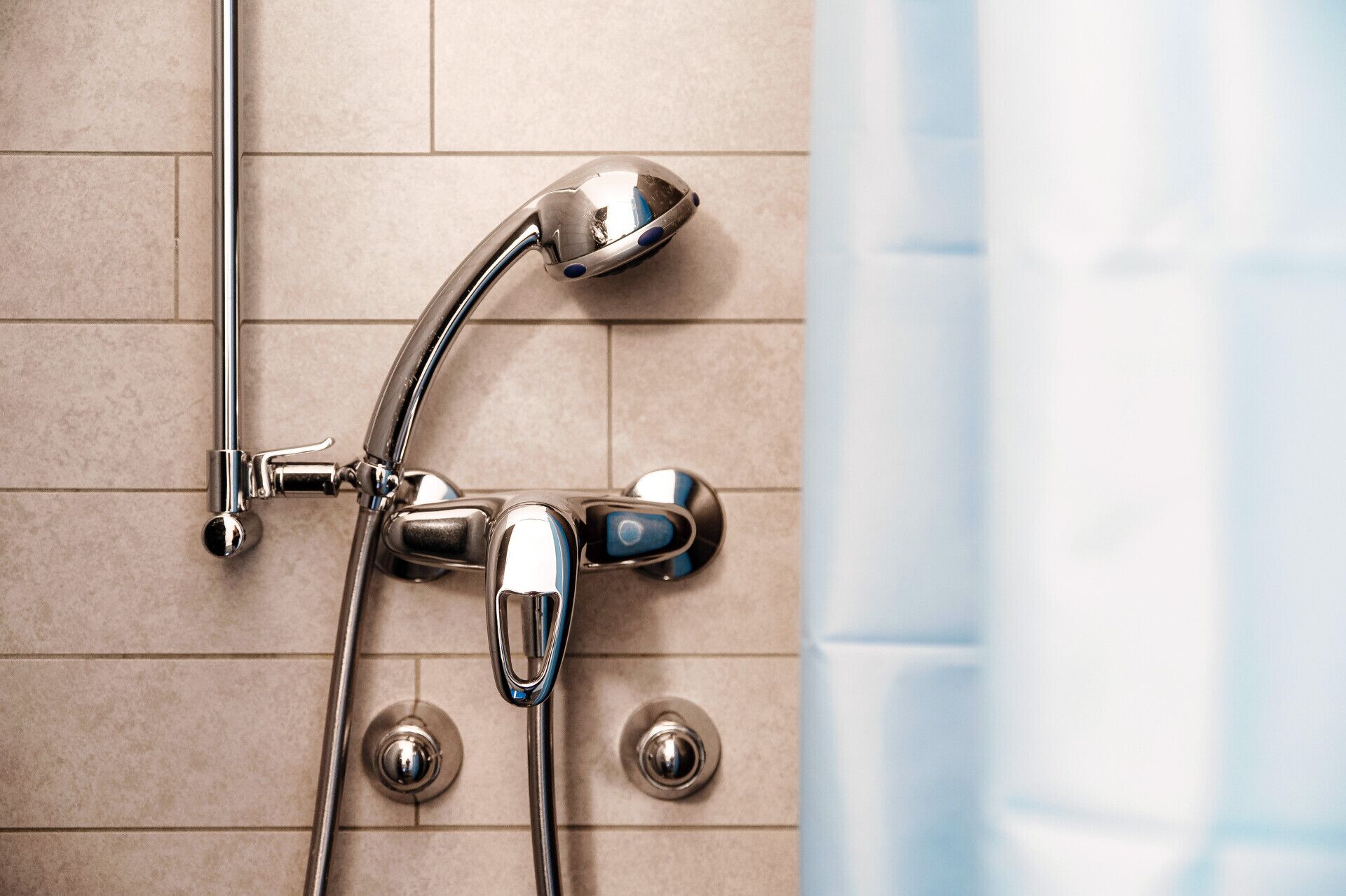 A shower with a chrome faucet and a handheld showerhead mounted on the wall.
