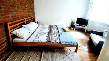 A bedroom with a wooden bed, a TV, and a window.