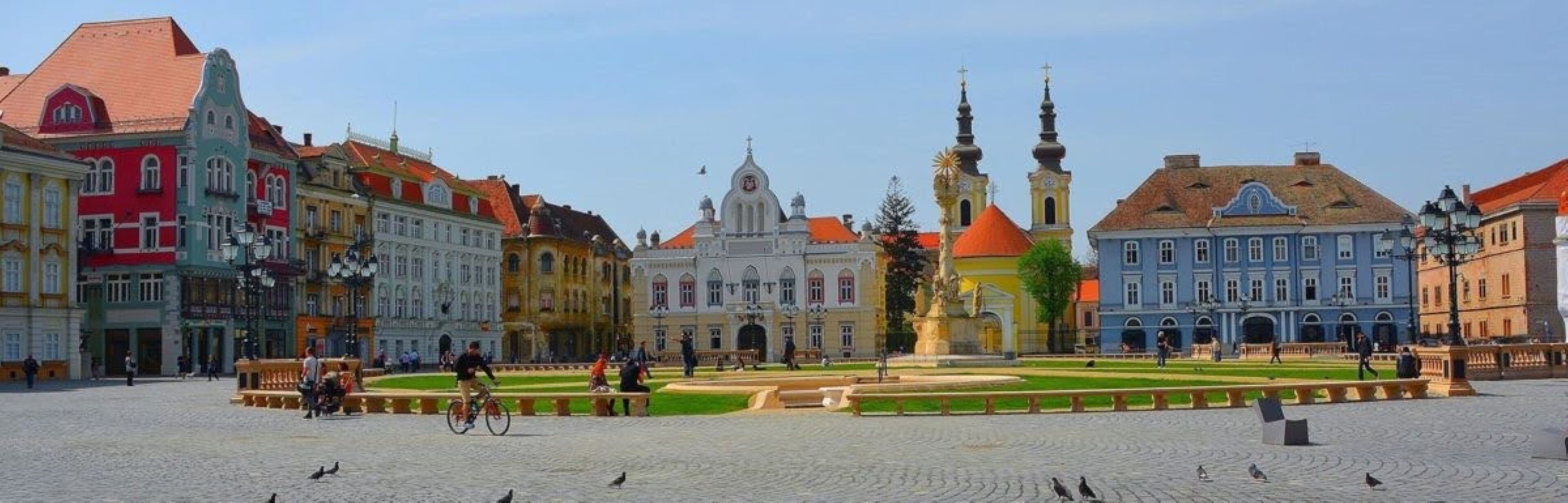 A historic square with a central fountain, surrounded by colorful buildings with varied architectural styles.