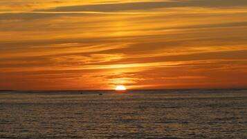 Un atardecer sobre el océano con un barco a lo lejos.