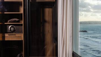 A room with a view of the sea, a built-in wardrobe with shelves, and a door with a keypad lock.