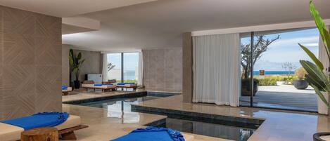 Un moderno espacio de spa con piscina, sillones de descanso y vistas al océano.