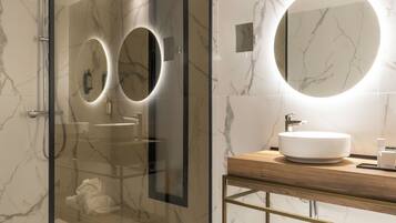 A modern bathroom with a glass-enclosed shower, a round mirror, and a wooden vanity with a sink.