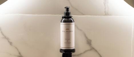 A bathroom with a marble wall, a black soap dispenser, and a set of white soap bars on a black tray.