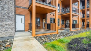 A multi-story residential building with balconies, a stone facade, and a landscaped garden area. - Pet Friendly Condo, Suncadia Pool Access (Cle Elum)