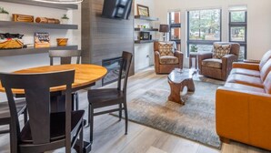 A modern living room with a wooden dining table, leather sofa, and armchairs. - Pet Friendly Condo, Suncadia Pool Access (Cle Elum)