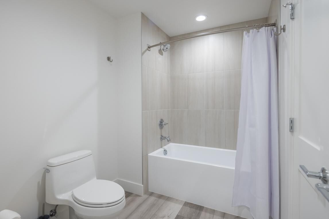 A bathroom with a toilet, a bathtub, and a shower curtain.