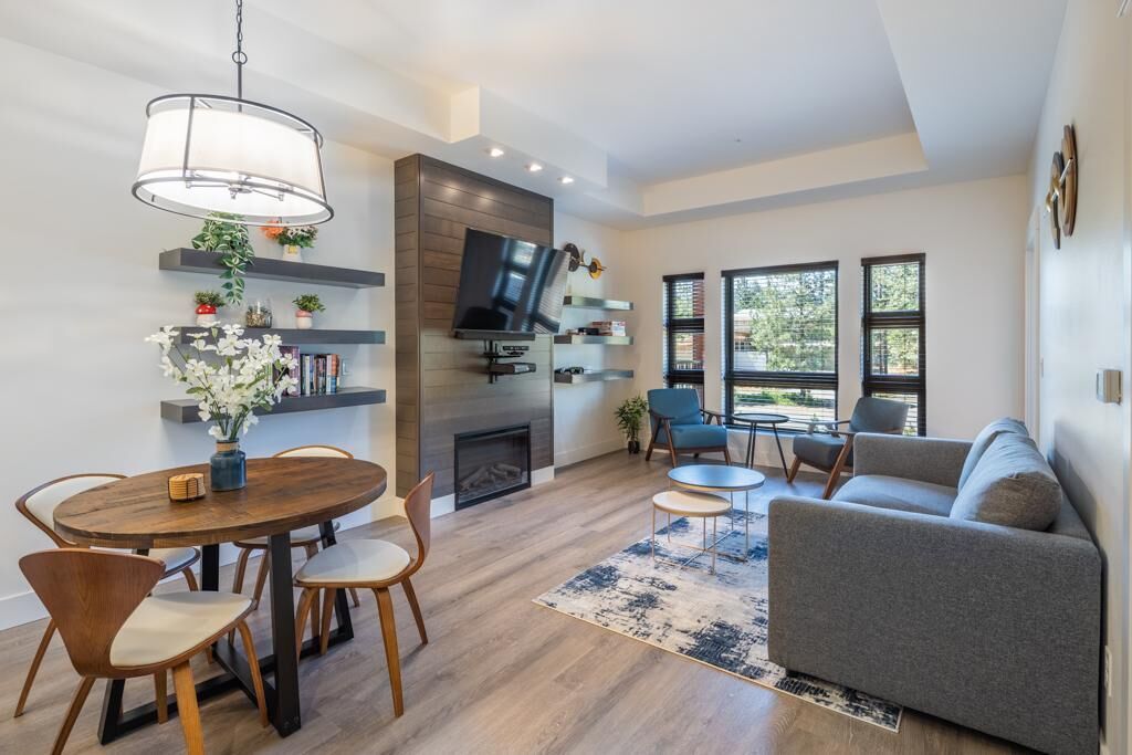 A modern living room with a fireplace, a dining area with a round table, and a sofa.