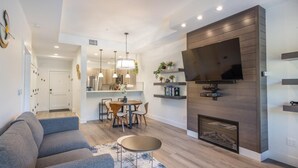 A modern living room with a sofa, a dining table, and a fireplace. - Central Condo with Suncadia Pool Access (Cle Elum)