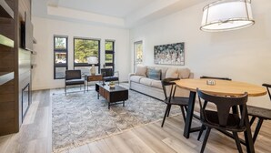 A modern living room with a dining area, large windows, a sofa, and a coffee table. - Family Friendly w/ Suncadia Pool Access (Cle Elum)