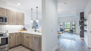 Une cuisine moderne avec des meubles en bois, des appareils électroménagers en acier inoxydable et des luminaires suspendus.