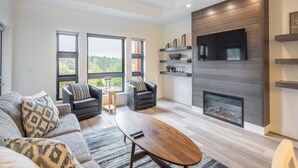 A modern living room with a fireplace, a sofa set, and a television mounted on the wall. - Golf View Condo & Suncadia Pool Access (Cle Elum)