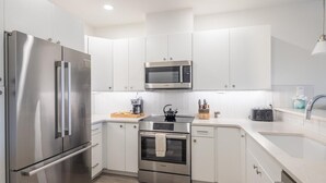 A modern kitchen with stainless steel appliances, white cabinetry, and a built-in oven. - Golf View Condo & Suncadia Pool Access (Cle Elum)