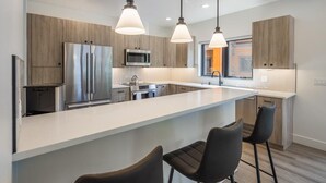 A modern kitchen with a central island, stainless steel appliances, and pendant lighting. - Pet Friendly Condo, Suncadia Pool Access (Cle Elum)