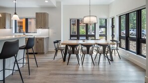 A modern kitchen with a central island, bar stools, and a dining table with chairs. - Golf View Condo & Suncadia Pool Access (Cle Elum)