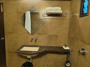 A bathroom with a granite countertop sink, a mirror, a towel rack, and a shower. - Hotel Heritage 2001-Nagpur (Nagpur)