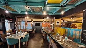 A restaurant with multiple tables and chairs, a TV screen on the wall, and a variety of decorative elements. - Hotel Heritage 2001-Nagpur (Nagpur)