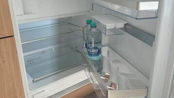 An open refrigerator with two bottles of water, a glass shelf, and a freezer compartment.