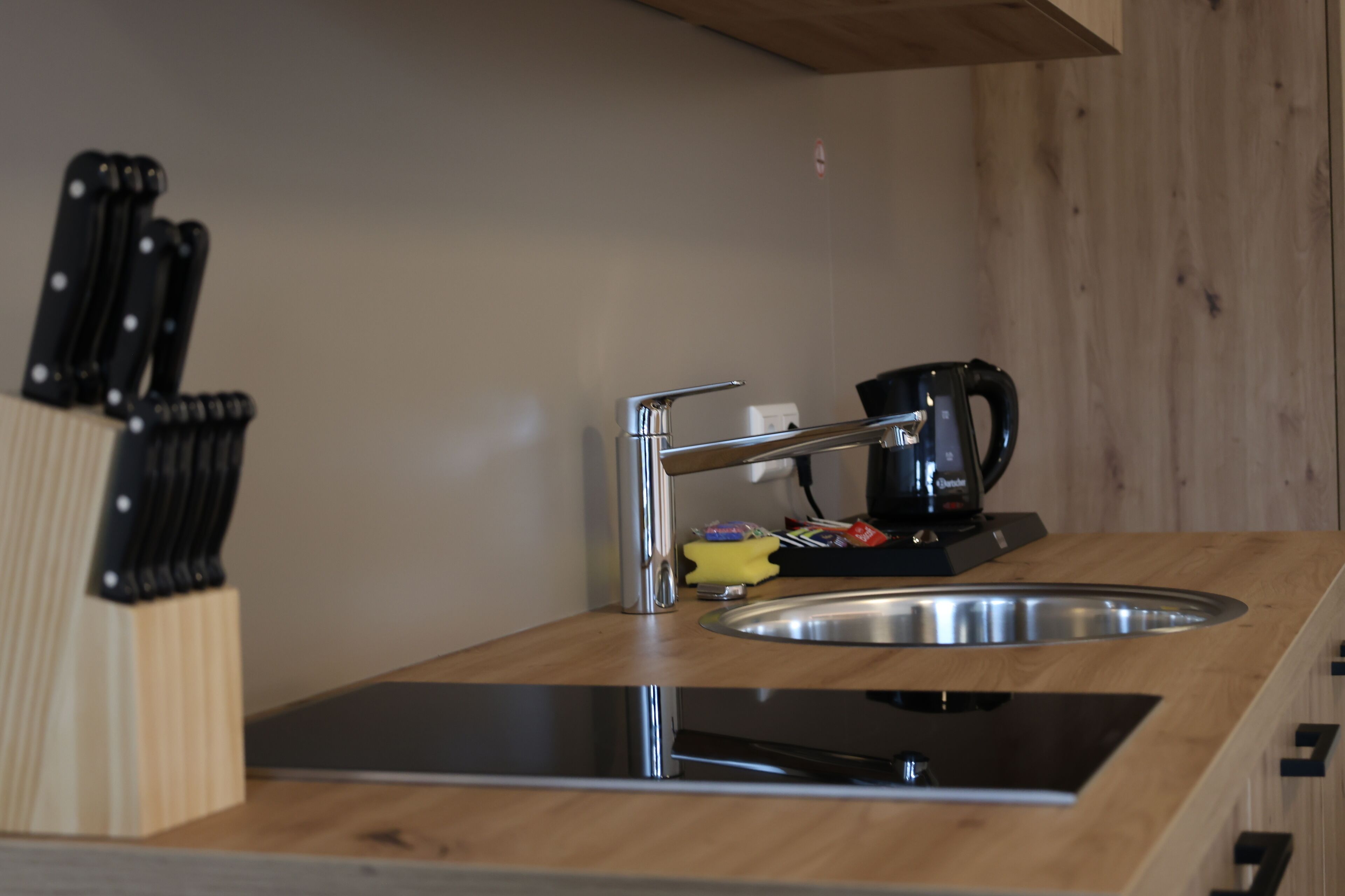 A kitchen with a stainless steel sink, a coffee maker, and a knife block.