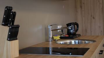 A kitchen with a stainless steel sink, a coffee maker, and a knife block.