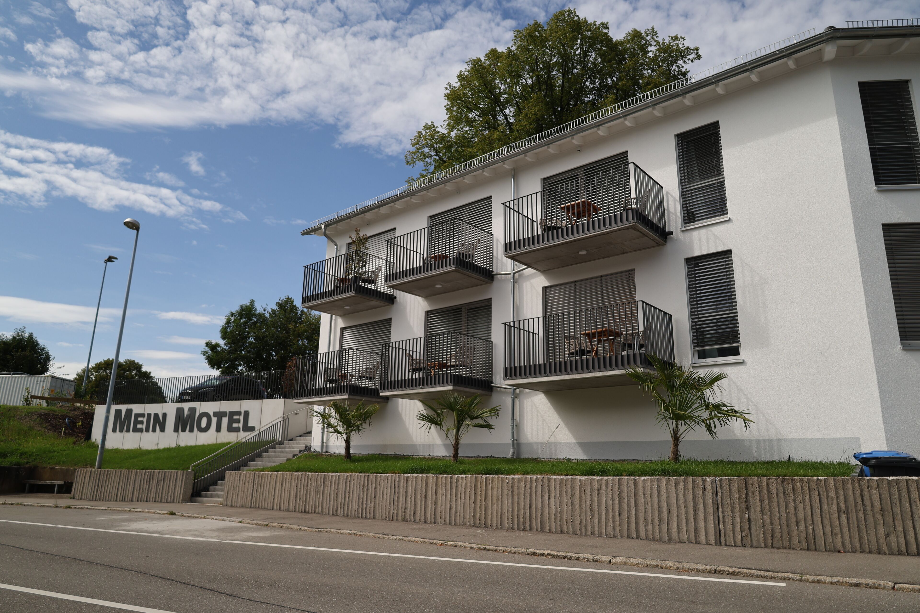 A modern building with multiple balconies and a sign reading "Mein Motel".