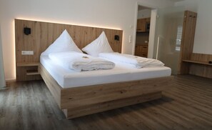 A modern bedroom with a wooden headboard, a large bed with white linens, a wooden floor, and built-in storage cabinets. - MEIN MOTEL - Self Check-in - (Oberndorf am Neckar)