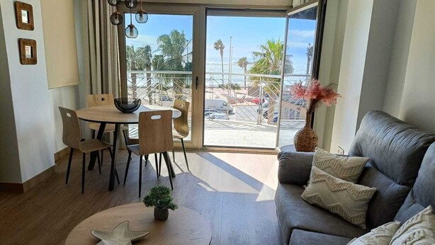 A modern living room with a grey sofa, a round coffee table, and a dining area with a table and chairs.