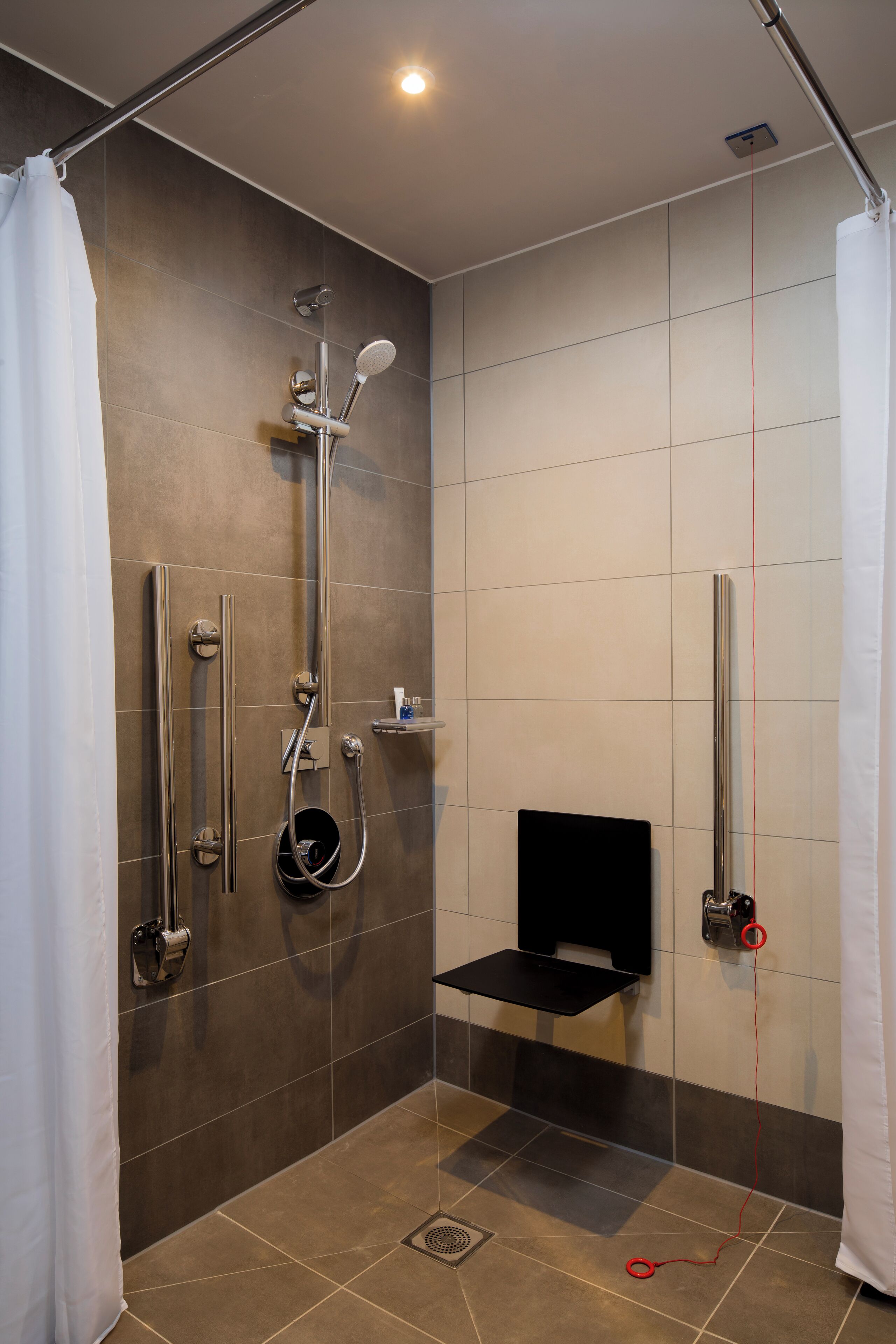 A modern shower area with a handheld showerhead, a wall-mounted faucet, and a handheld showerhead.