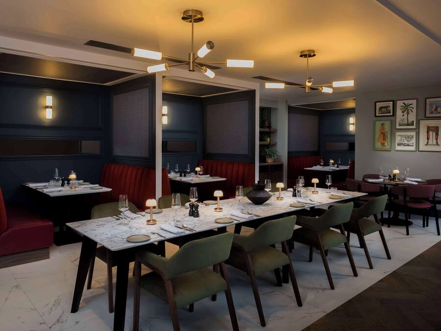 Un restaurant doté d’une longue table à manger, de plusieurs banquettes et d’un ventilateur de plafond.
