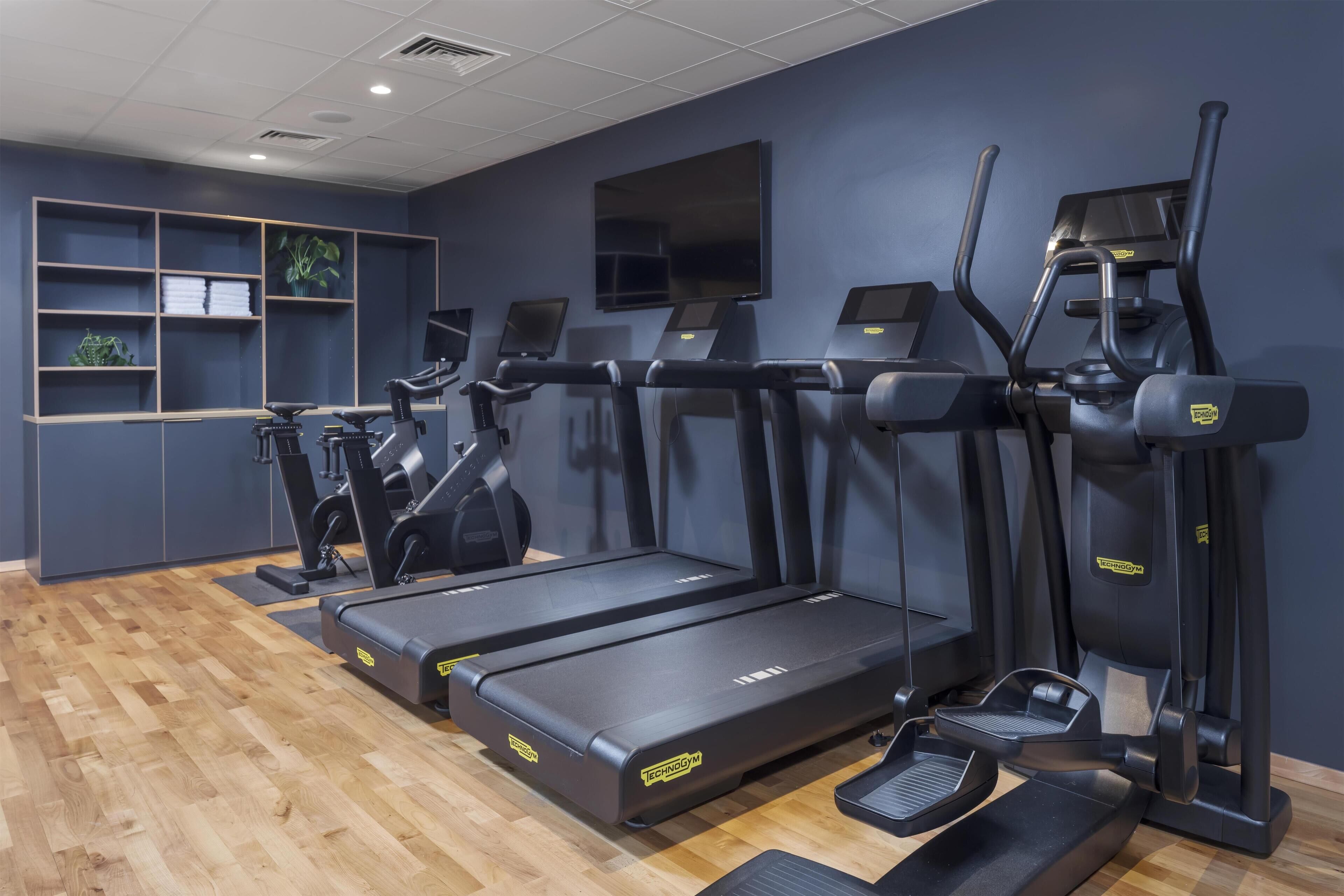 Et fitnesscenter med løbebånd, crosstrainere og styrkemaskiner.