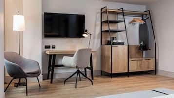 A modern room with a desk, two chairs, a TV, a lamp, and a wooden cabinet with shelves.