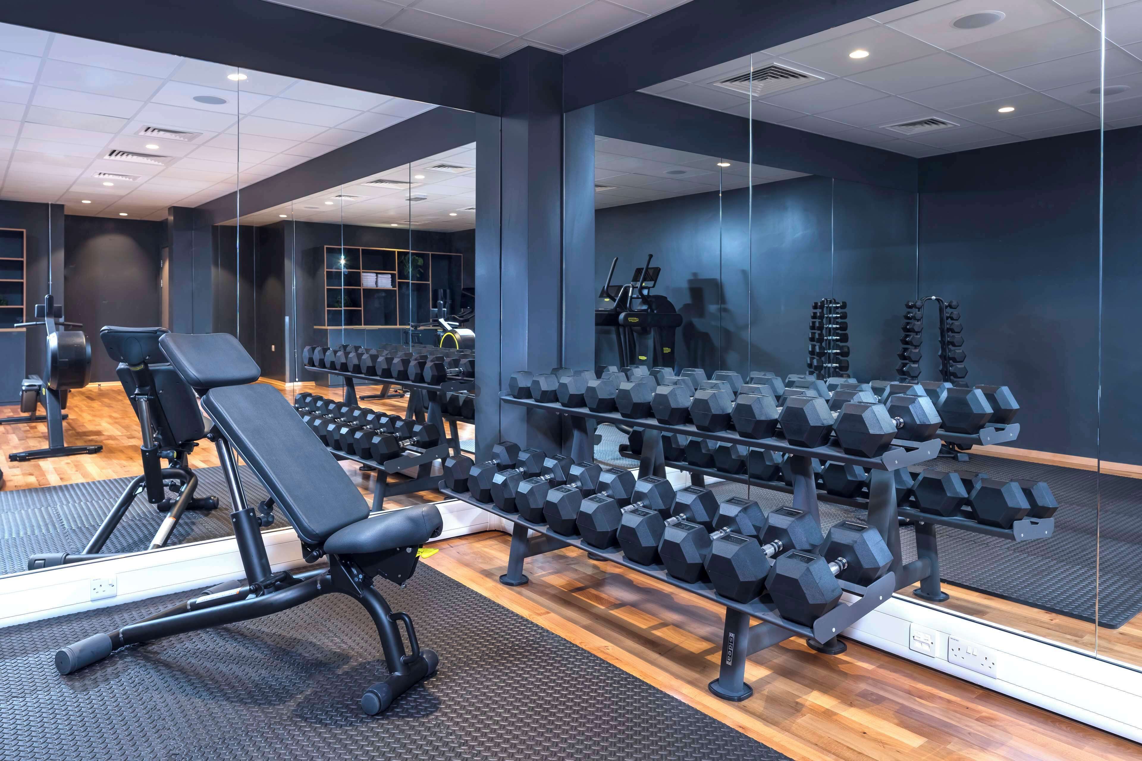 A gym with exercise equipment, including benches, dumbbells, and treadmills.