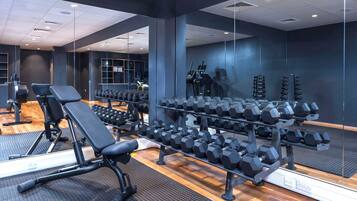 A gym with exercise equipment, including benches, dumbbells, and treadmills.