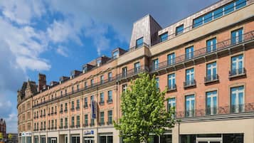Un hôtel à plusieurs étages, doté d’une façade classique, qui allie des éléments en brique et des éléments en verre modernes.