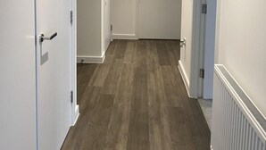A hallway with wooden flooring, white walls, and a radiator on the right.