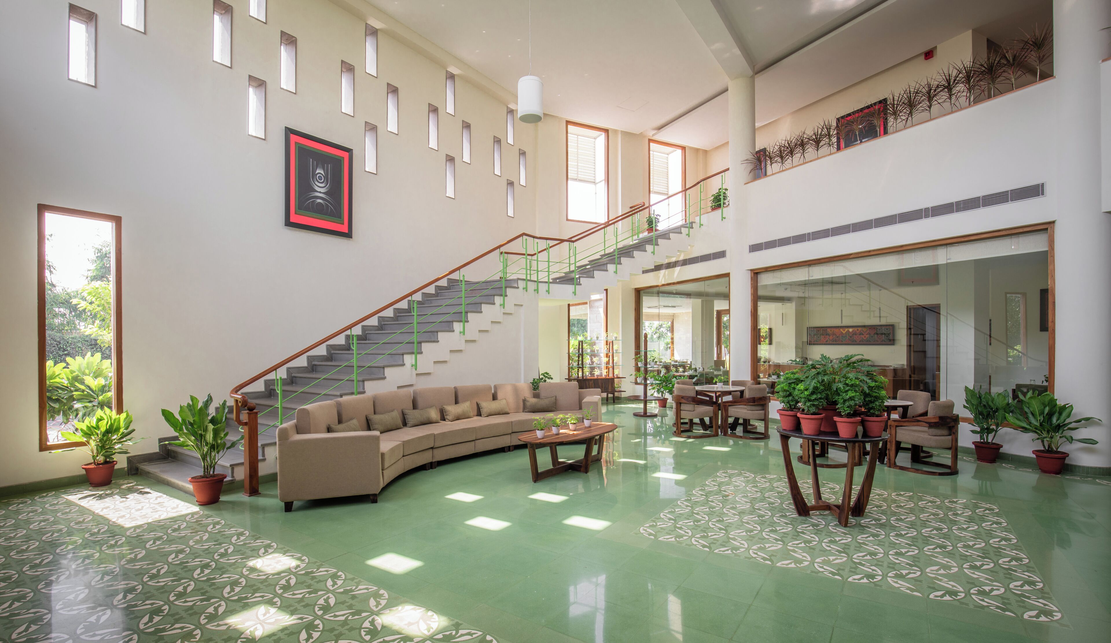A spacious interior with a curved sofa, a staircase, and a dining area with multiple chairs and tables.