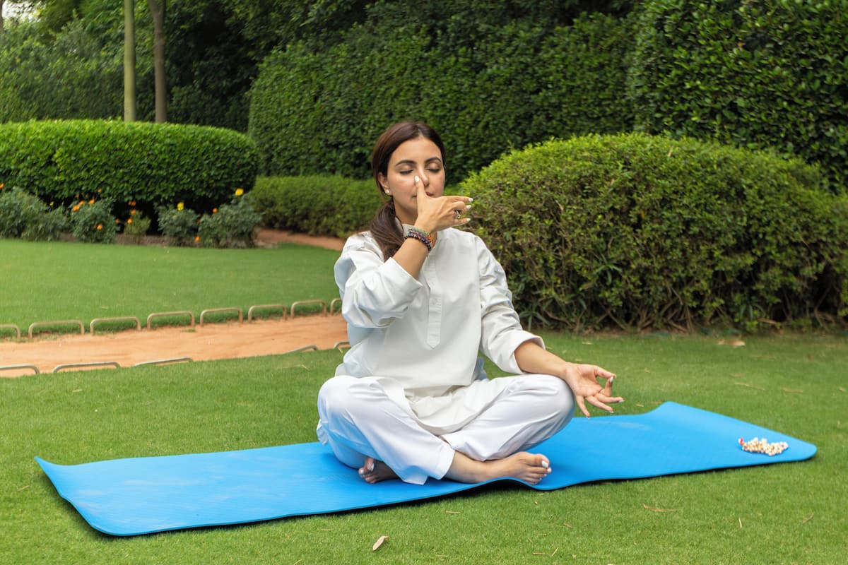 A person sitting on a blue exercise mat outdoors.