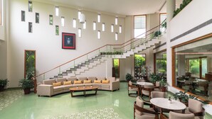 A spacious lobby with a staircase, seating area, and potted plants. - Naad Wellness (Sonepat)