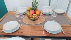 A dining table set with white plates, cutlery, and a fruit basket in the center. - Charmant Appartement au Pied D'un Parc Arboré (Clichy)