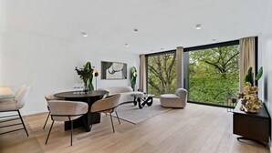 Un salon moderne avec un coin repas, de grandes fenêtres et une vue sur la verdure.