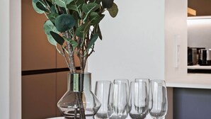 Une table à manger sur laquelle se trouve un vase en verre contenant des feuilles vertes et six verres à vin.