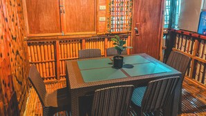 Un interior de madera con una mesa, sillas, una planta en maceta y un televisor en la pared.