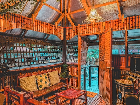 A wooden interior with a high ceiling, a wooden bench, a table, and a patterned wall.