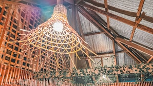 Un interior rústico con estructura de techo de madera, una lámpara colgante y una puerta con un letrero pequeño.