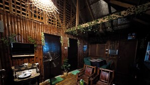 Una habitación acogedora con paredes de madera, un ventilador, un televisor y una zona de comedor con sillas y una mesa.